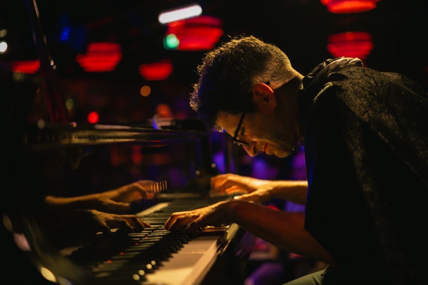 Greg Spero playing piano on stage under red lights